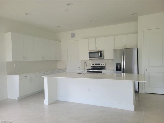 Kitchen with appliances with stainless steel finishes, light countertops, tasteful backsplash, a kitchen island with sink, and recessed lighting | Image 4
