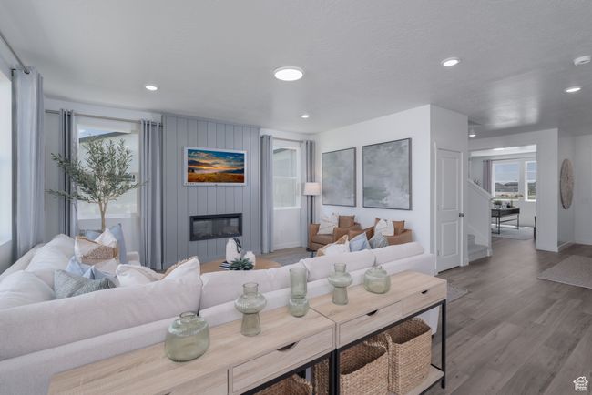 Living area featuring wood finished floors, a large fireplace, stairway, and recessed lighting | Image 26
