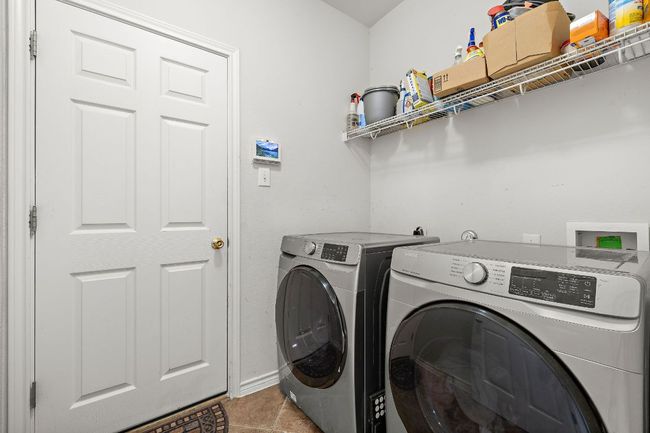 Washroom featuring washer and dryer, overhead storage, and light tile patterned floors | Image 23