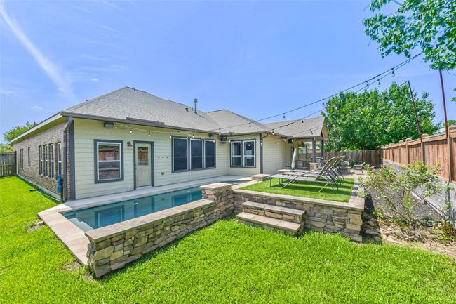 Charming home with a sleek pool, stone patio area, and well-maintained lawn. Ideal for outdoor relaxation and entertaining. | Image 31