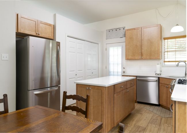 Kitchen with appliances with stainless steel finishes, light wood-style flooring, light countertops, a center island, and tasteful backsplash | Image 11