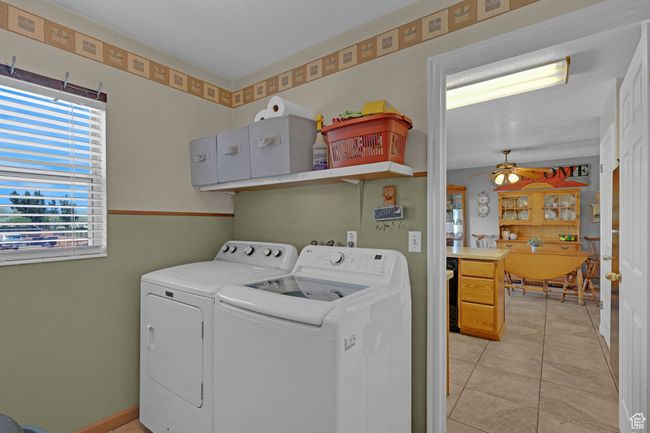Laundry area with separate washer and dryer, a ceiling fan, and light tile patterned flooring | Image 21