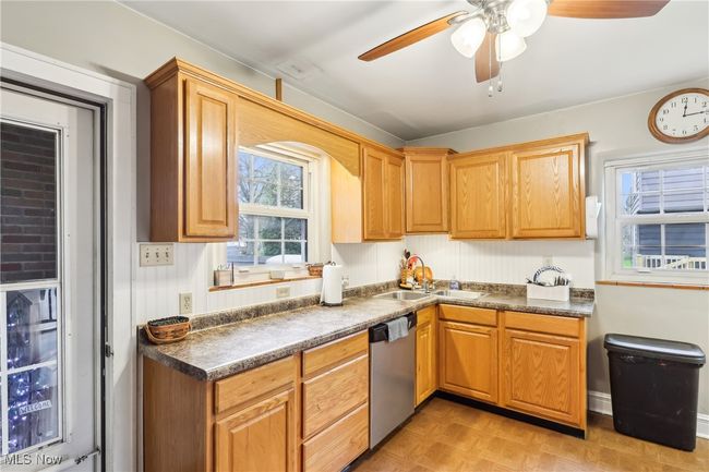 Kitchen with dishwasher, dark countertops, a ceiling fan, and a sink | Image 12