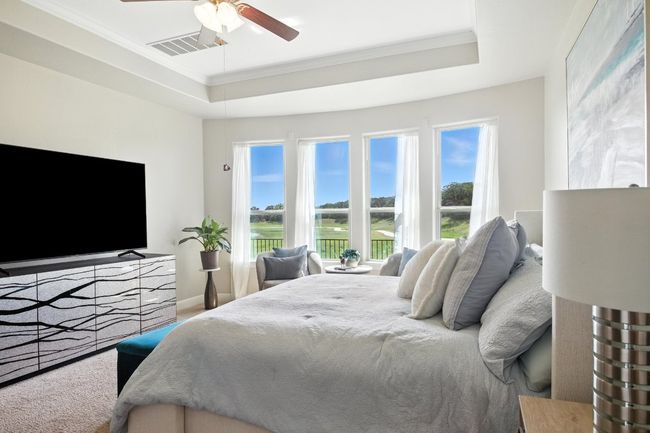 Bedroom with a tray ceiling, multiple windows, crown molding, and a ceiling fan | Image 17