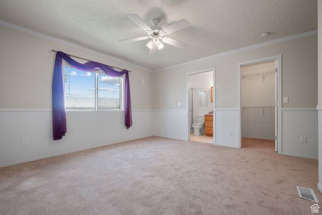 Unfurnished bedroom with a textured ceiling, a spacious closet, crown molding, carpet, and ensuite bathroom | Image 14