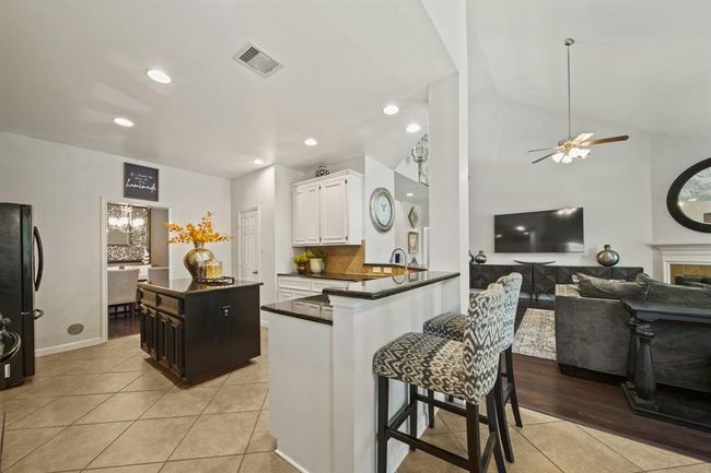 This open-concept kitchen features a raised breakfast bar overlooking the family room, perfect for casual dining or entertaining guests. | Image 20