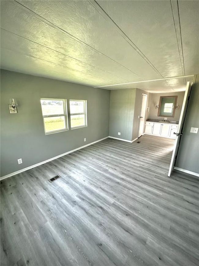 Unfurnished living room with baseboards, wood finished floors, and a textured ceiling | Image 11