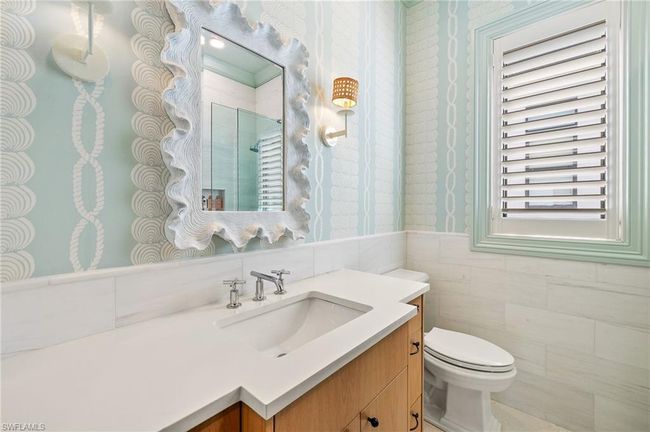 Full bath featuring a tile shower, wallpapered walls, a wainscoted wall, toilet, and vanity | Image 31