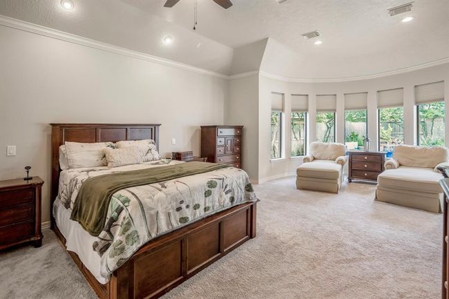 The spacious primary bedroom suite is located downstairs, featuring a large sitting area surrounded by a wall of windows offering spectacular views of the calming backyard. | Image 20