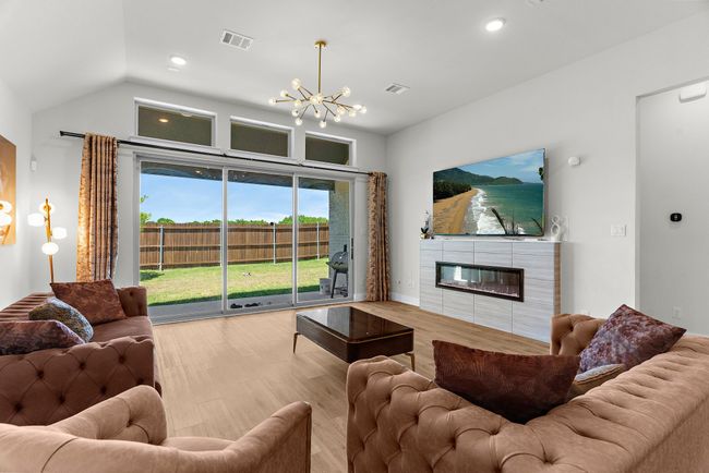 Living room featuring a chandelier, a tiled fireplace, wood finished floors, recessed lighting, and lofted ceiling | Image 14