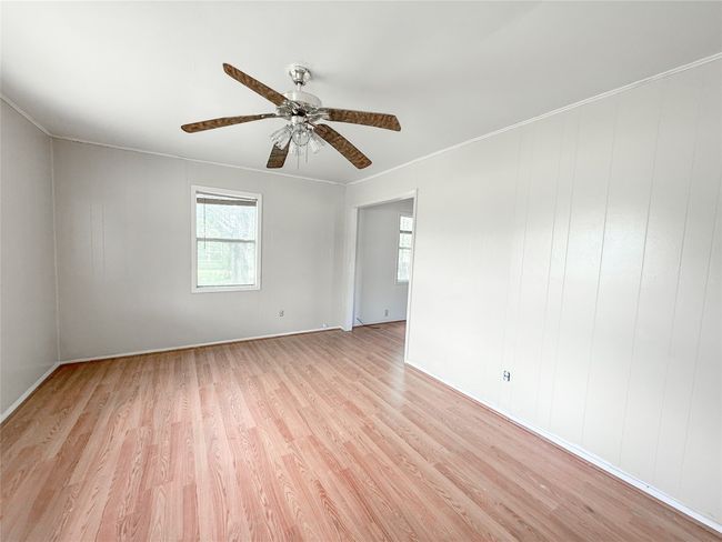Unfurnished room with crown molding, ceiling fan, baseboards, and light wood-style floors | Image 16