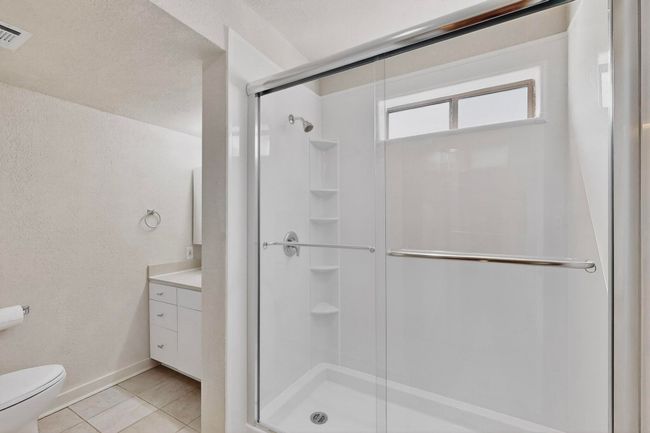 Bathroom with light tile patterned flooring, a stall shower, vanity, a textured wall, and a textured ceiling | Image 27