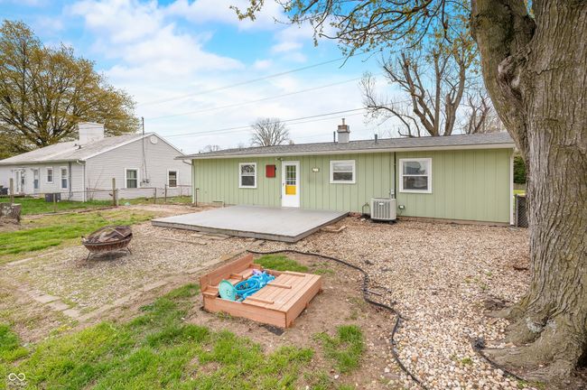 rear view of house featuring central air condition unit, a chimney, a deck, an outdoor fire pit, and fence | Image 8