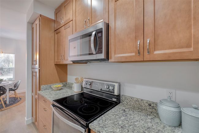 Kitchen featuring appliances with stainless steel finishes, light stone counters, light wood finished floors, and light brown cabinets | Image 7