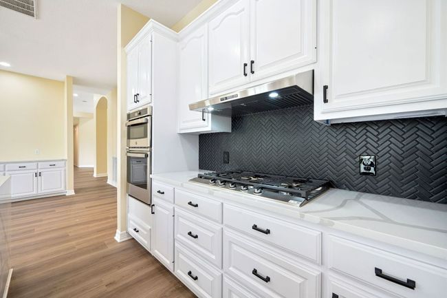 Chic matte black tile backsplash and plentiful white cabinetry. | Image 15