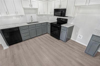 Kitchen with sink, black appliances, white cabinets, gray cabinetry, and decorative backsplash | Image 3