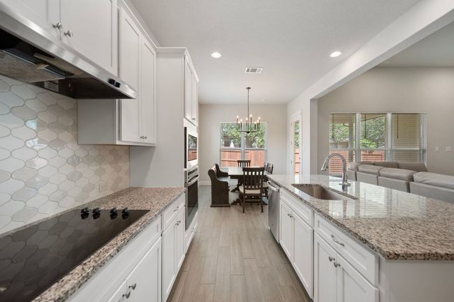 Kitchen with under cabinet range hood, a sink, stainless steel appliances, recessed lighting, and tasteful backsplash | Image 9