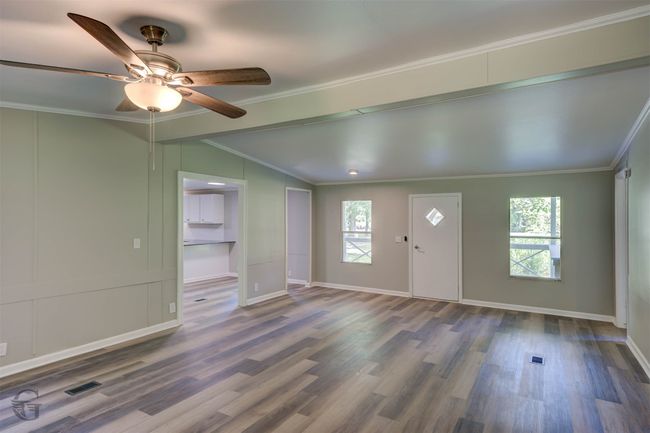 Entrance foyer with vaulted ceiling, ornamental molding, plenty of natural light, ceiling fan, and wood finished floors | Image 7