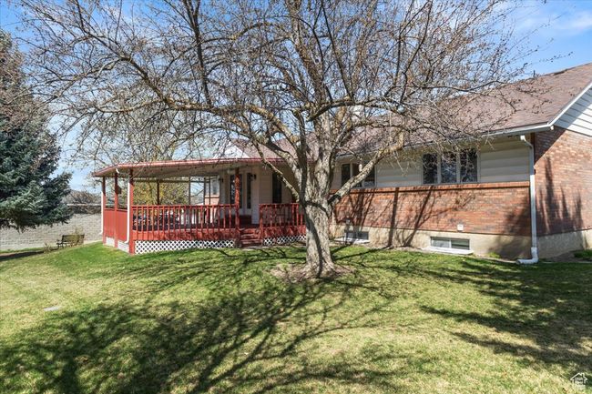 Back of house with brick siding, a deck, and a lawn | Image 37