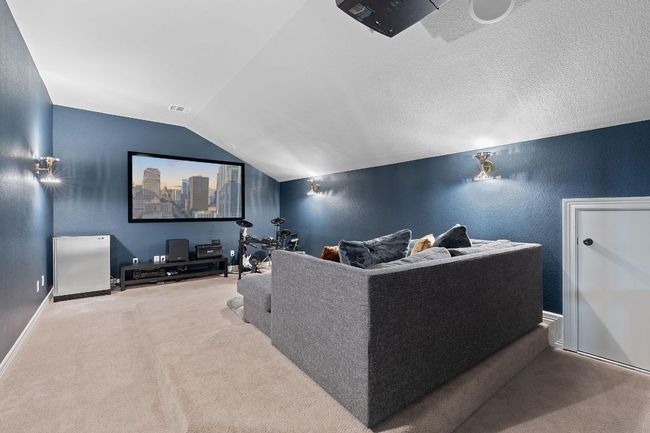 Home theater room featuring carpet floors, vaulted ceiling, a textured wall, and baseboards | Image 16