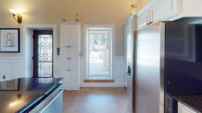 Kitchen featuring a decorative wall, white cabinets, wainscoting, stainless steel refrigerator with ice dispenser, and dark stone countertops | Image 10