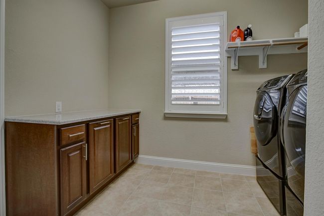 Laundry area featuring washing machine and clothes dryer, light tile patterned floors, and cabinet space | Image 19