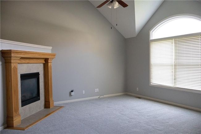 Unfurnished living room featuring carpet flooring, a tiled fireplace, and a ceiling fan | Image 4