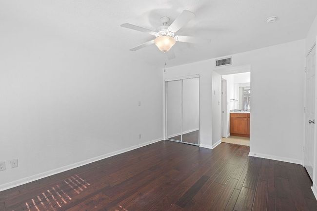 Unfurnished bedroom with dark wood finished floors, baseboards, visible vents, and a closet | Image 21