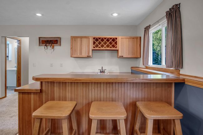 Kitchen with a breakfast bar area, a sink, recessed lighting, light brown cabinetry, and light carpet | Image 24