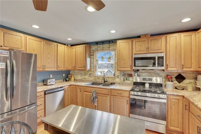 Kitchen featuring appliances with stainless steel finishes, light brown cabinetry, backsplash, and recessed lighting | Image 13