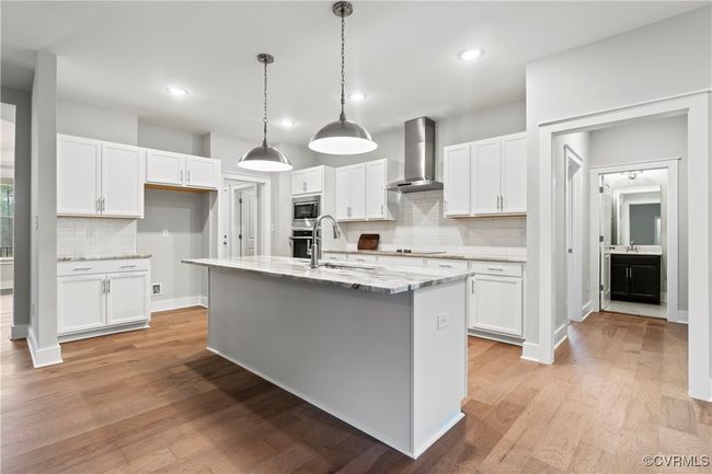 Photo represents the plan, not the actual home. Design selections may vary. The well-appointed kitchen boasts a center island, quartz countertops and a walk-in pantry. The adjoining dining area features a sliding glass door leading to the back porch. | Image 4