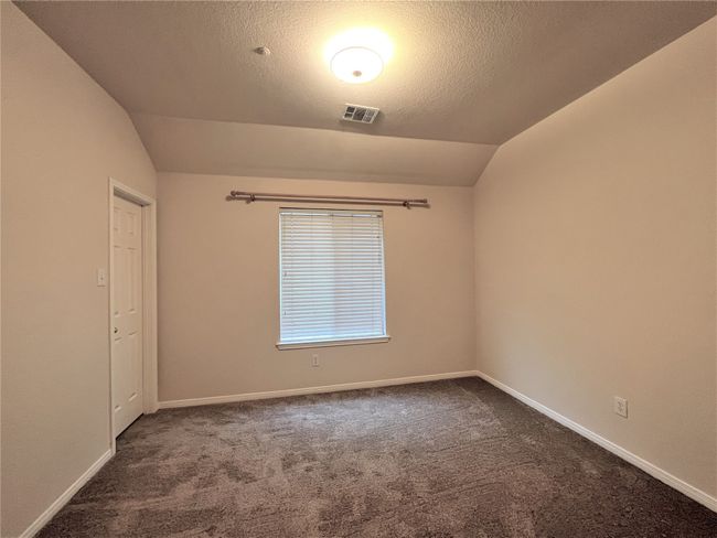 Spare room featuring vaulted ceiling, carpet floors, and a textured ceiling | Image 13
