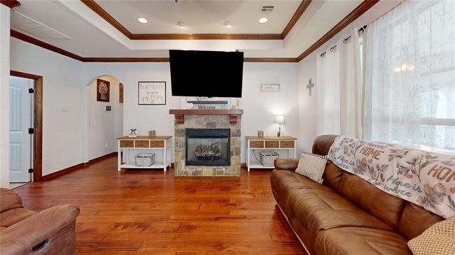 Living area with arched walkways, hardwood / wood-style floors, visible vents, and a raised ceiling | Image 13