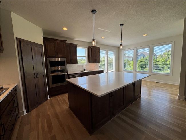 Kitchen with stainless steel appliances, dark wood-type flooring, light countertops, a kitchen island, and recessed lighting | Image 17