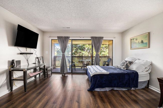 Bedroom featuring a textured ceiling, dark wood-style flooring, and access to exterior | Image 18