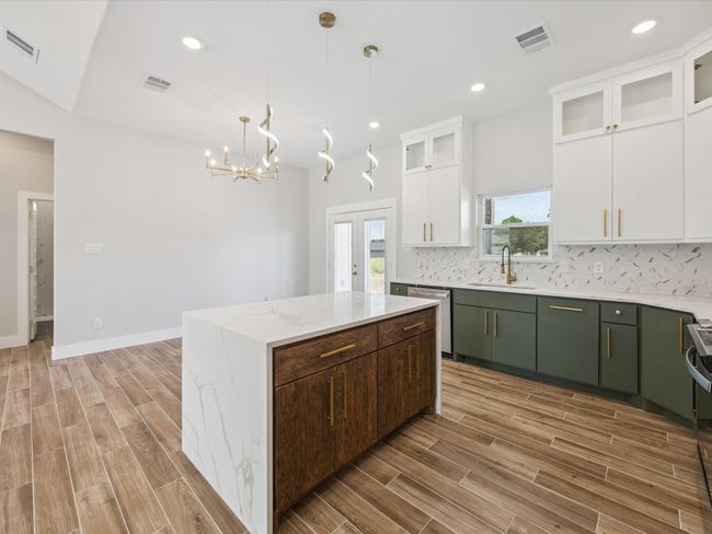 Kitchen featuring dishwasher, light wood-style floors, tasteful backsplash, a kitchen island, and white cabinetry | Image 11