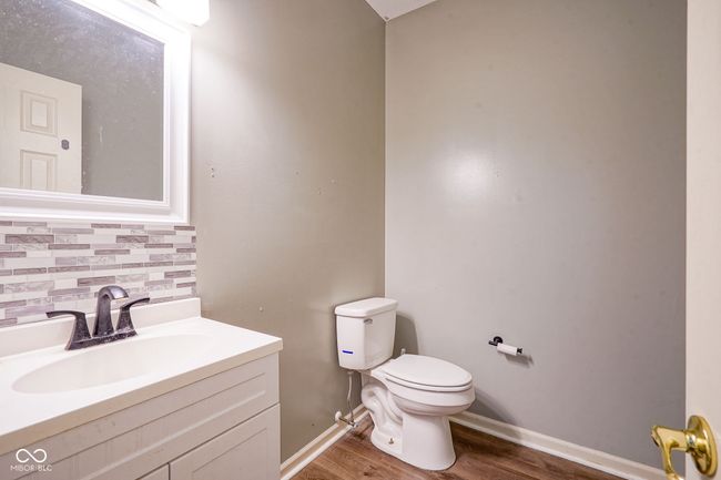 Half bathroom on main level featuring tasteful backsplash, wood finished floors, and vanity | Image 9