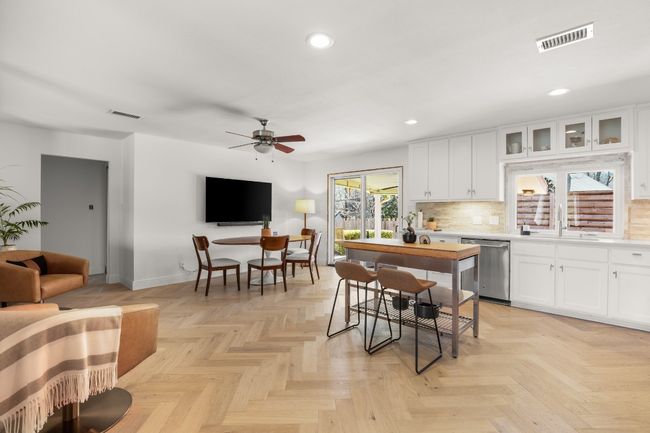 Kitchen with light countertops, visible vents, glass insert cabinets, white cabinets, and dishwasher | Image 13