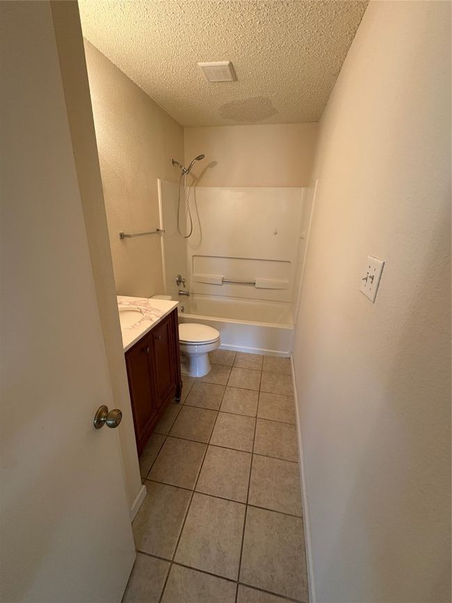Full bathroom featuring a textured ceiling, vanity, tile patterned floors, and shower combination | Image 14