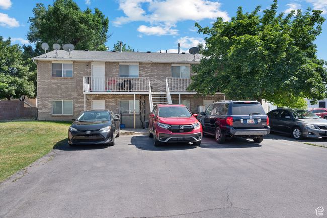 Townhome / multi-family property featuring brick siding, uncovered parking, a front lawn, and a balcony | Image 7