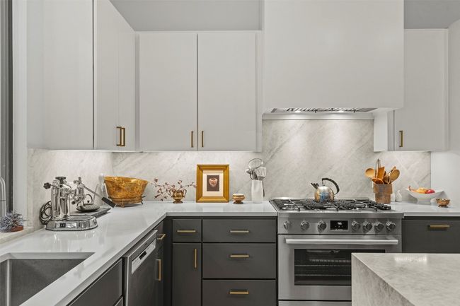 Kitchen featuring appliances with stainless steel finishes, light countertops, premium range hood, white cabinetry, and tasteful backsplash | Image 18