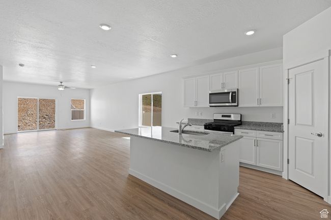 Kitchen featuring a sink, light stone counters, white cabinets, and appliances with stainless steel finishes | Image 5