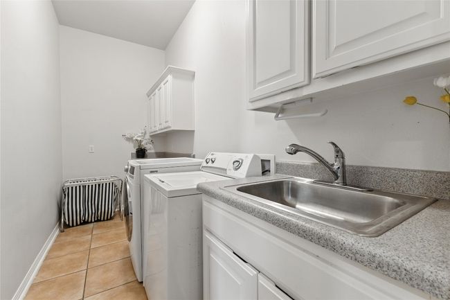 Laundry area featuring separate washer and dryer, cabinet space, and light tile patterned floors | Image 37