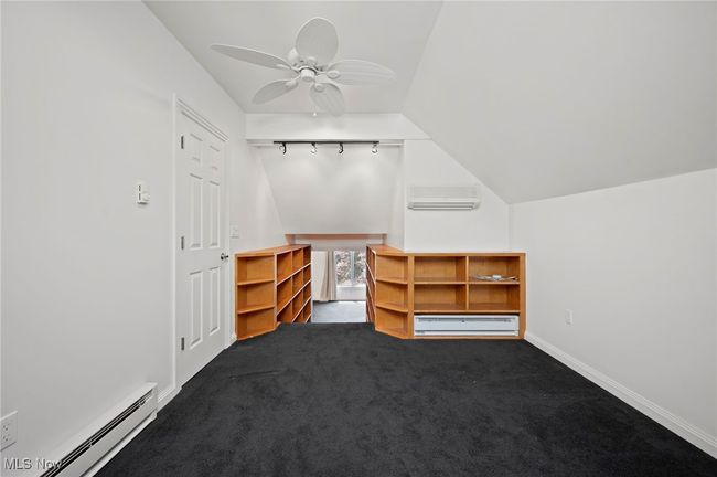 Additional storage, closet or loft space with baseboard heating, a baseboard radiator, vaulted ceiling, a wall unit AC, and a ceiling fan | Image 25