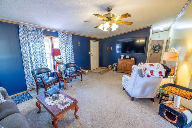 Living room with ornamental molding, a textured ceiling, a ceiling fan, and lofted ceiling | Image 17