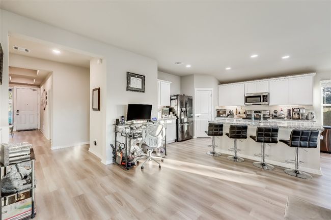 Kitchen with stainless steel appliances, light wood-style floors, a breakfast bar, recessed lighting, and white cabinetry | Image 8
