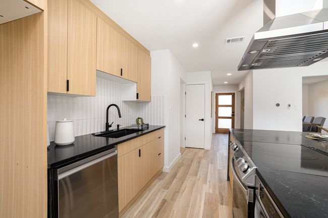 Kitchen featuring a sink, wall chimney range hood, light brown cabinetry, and dishwasher | Image 21