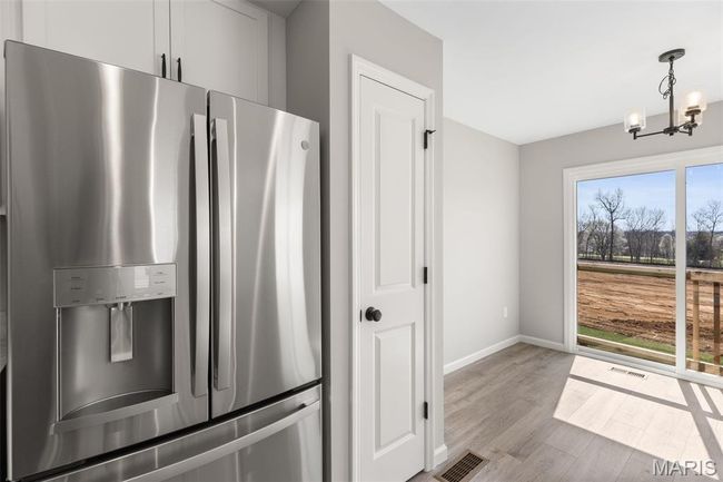 Kitchen with stainless steel fridge, a chandelier, wood finished floors, baseboards, and decorative light fixtures | Image 13