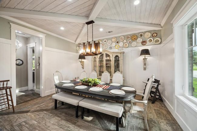 The formal dining room exudes sophistication, featuring elegant block paneling and a cross-beam ceiling with lap siding. A custom hand-forged chandelier illuminates the space, adding a unique and timeless touch to this distinguished setting. | Image 6