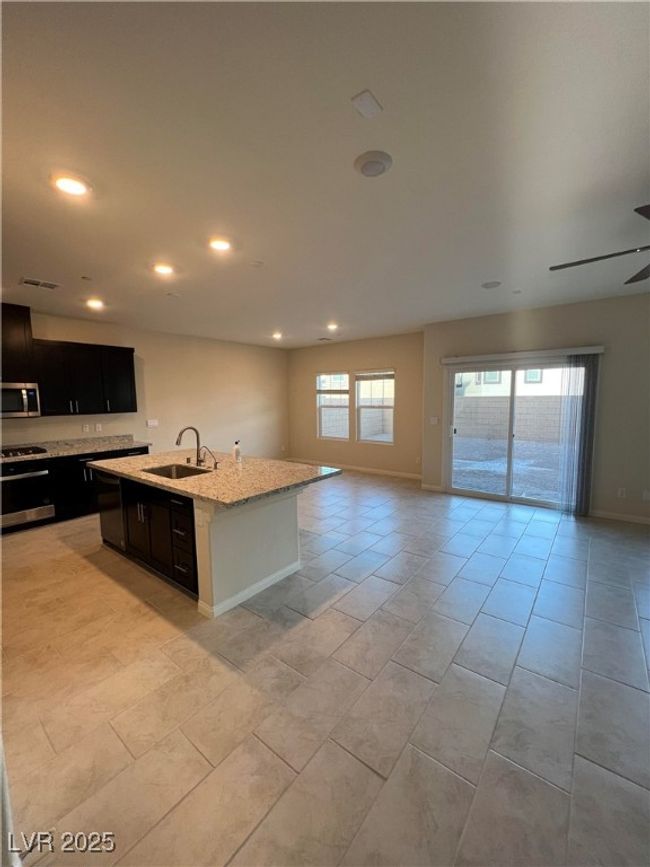 Kitchen with stainless steel microwave, open floor plan, a sink, recessed lighting, and dark cabinetry | Image 6